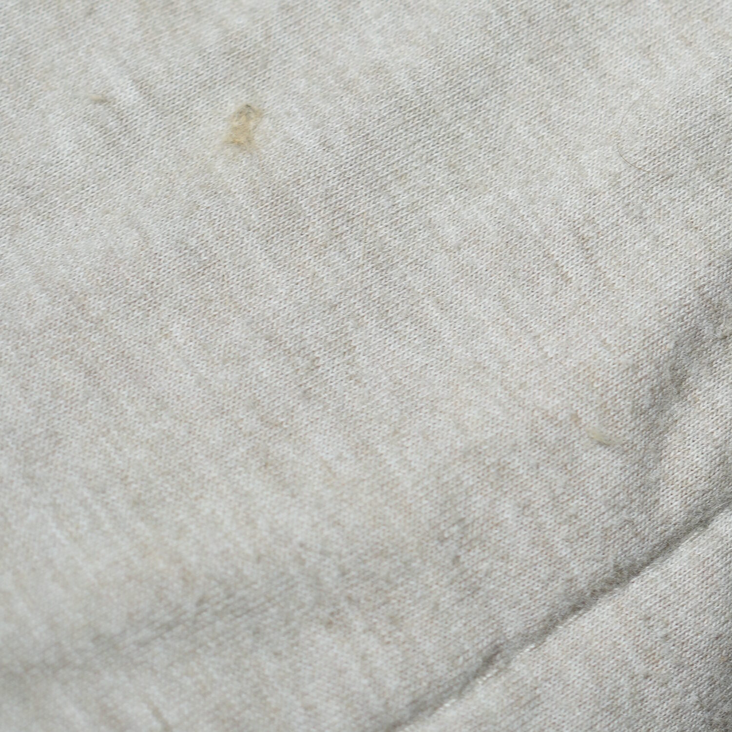 Macro close-up of cotton sheets showing loose fibers, embedded hair, and a fuzzy napped surface