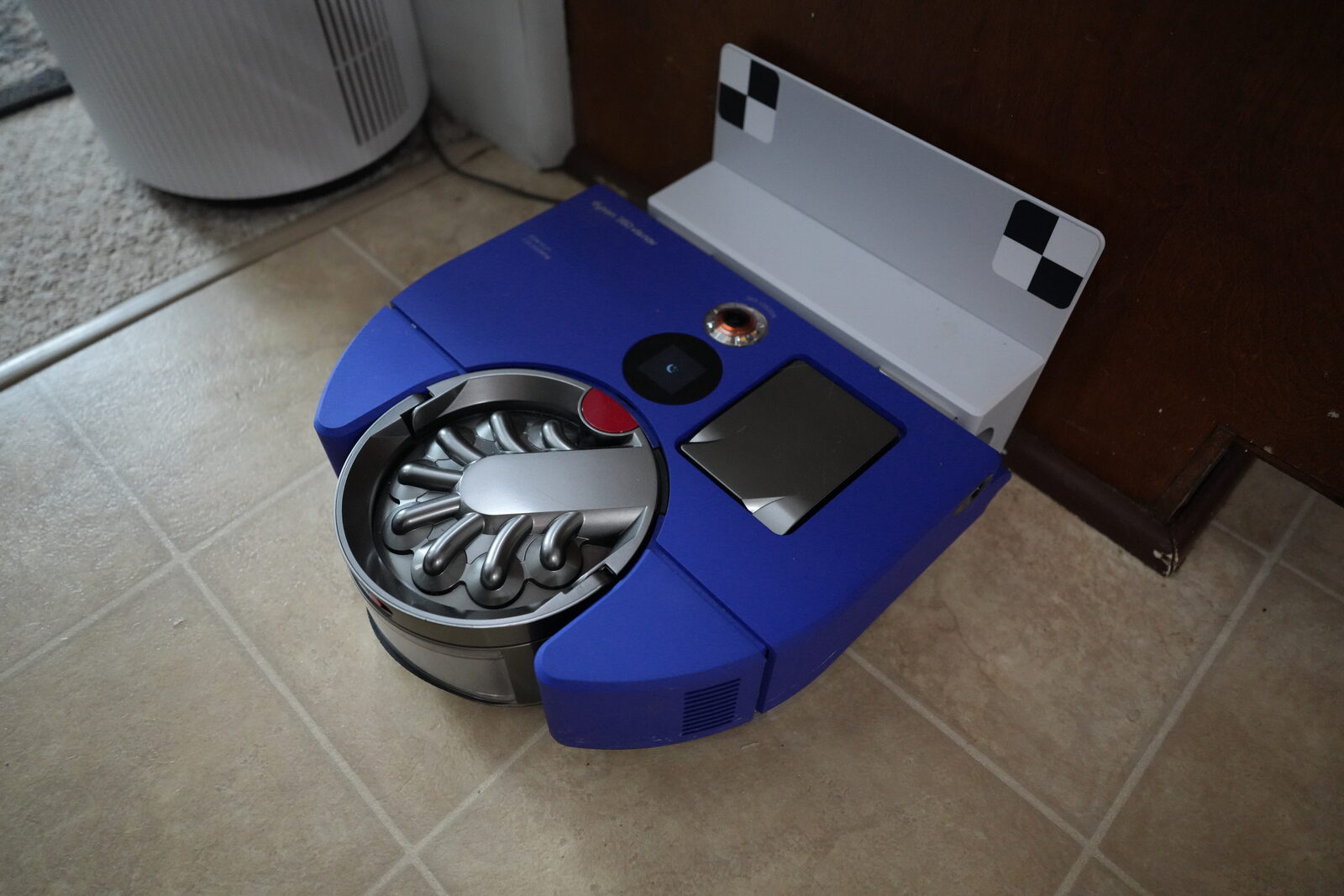 The Dyson 360 Vis Nav robot vacuum docked on its base in a hardwood-floor living room