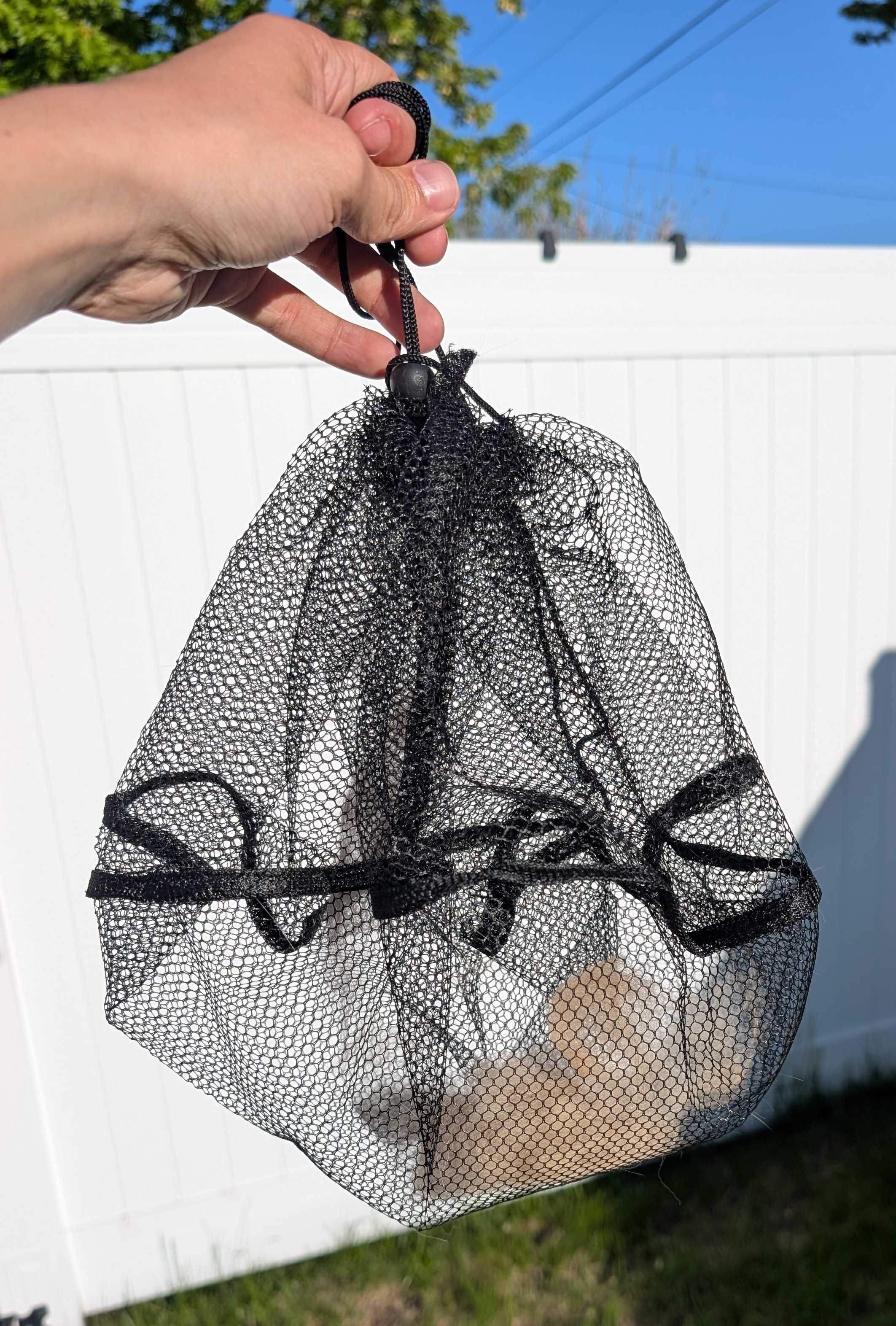 Loaded FurStopper mesh turned inside out, drawstring cinched, a sealed bag of cat fur ready to dispose