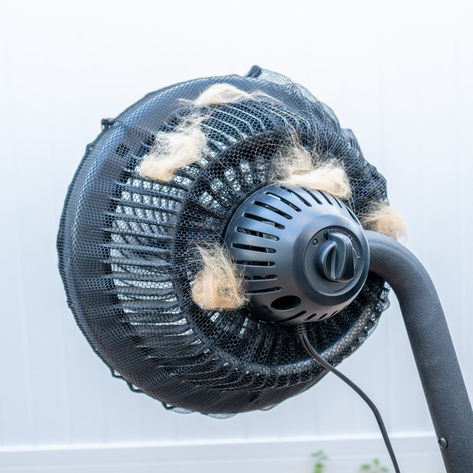 The FurStopper Fan Filter mesh on a pedestal fan, loaded with cat hair caught from the air over a week of running